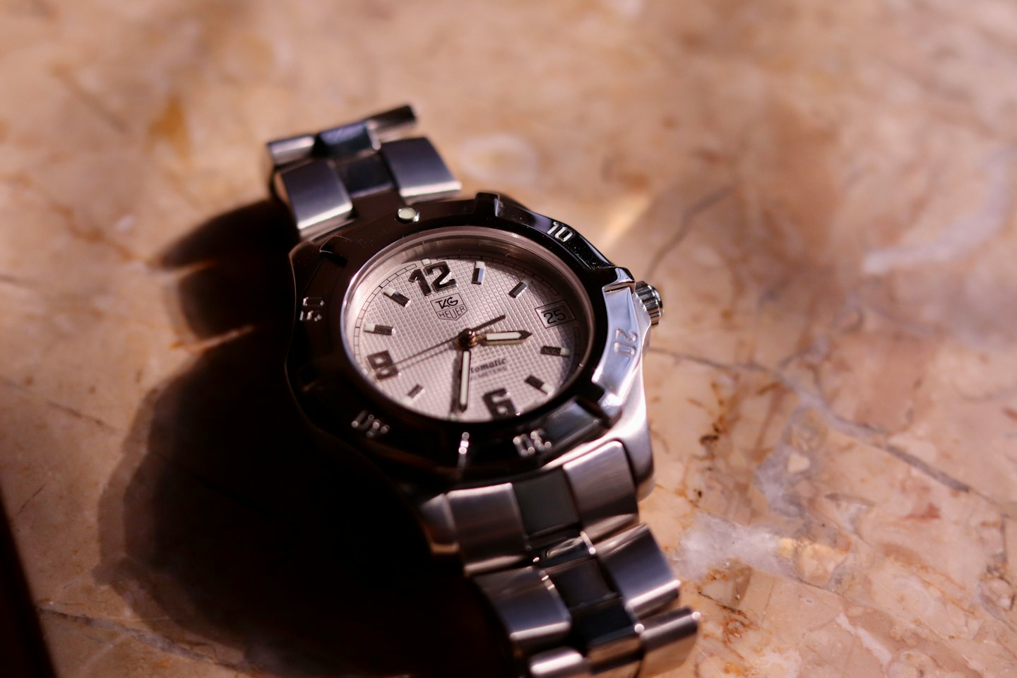 Une montre de luxe en acier inoxydable repose sur une surface en marbre.