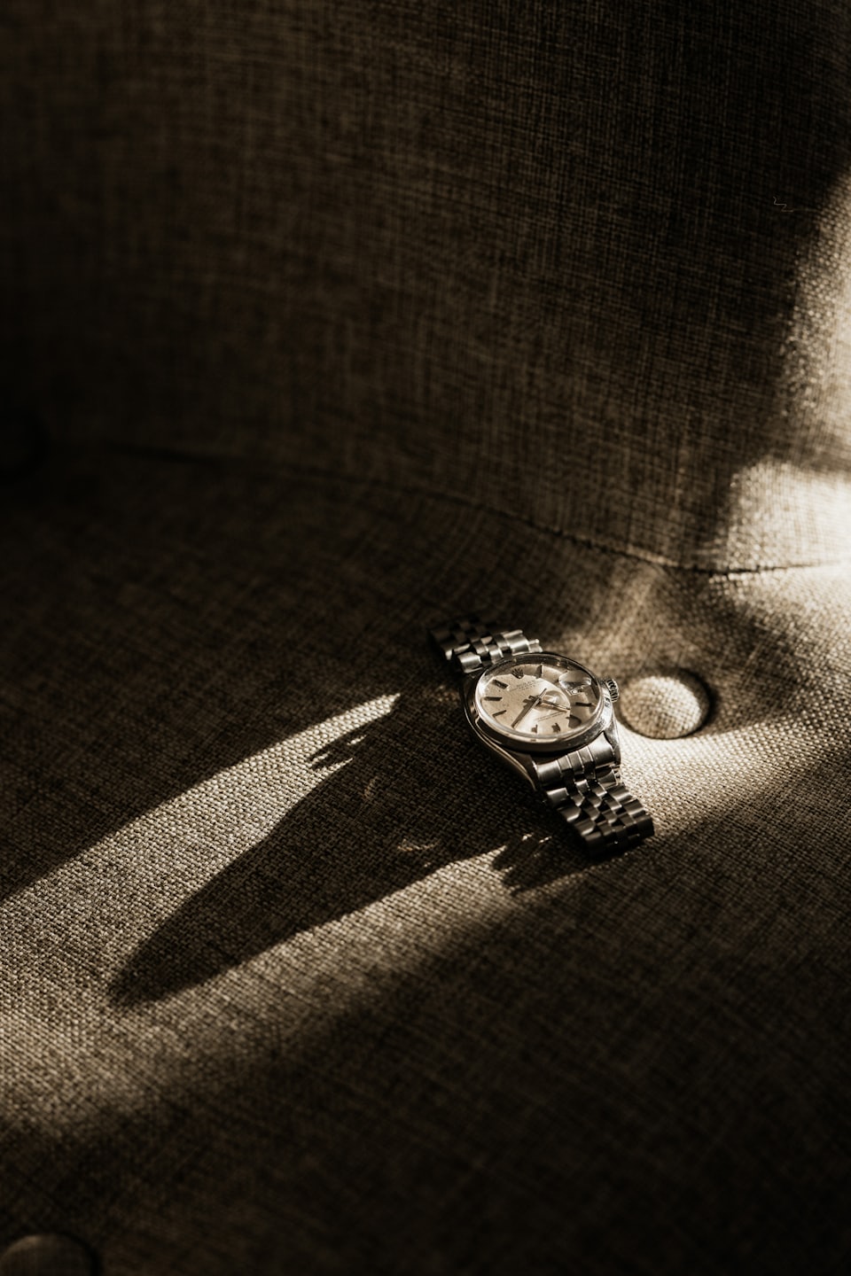 Montre bracelet en argent avec bracelet en métal sur tissu gris foncé.